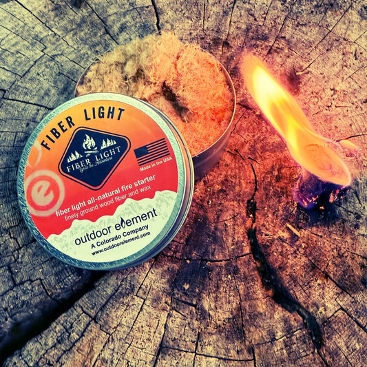 Fiber Light fire starter can on a wooden surface with a flame