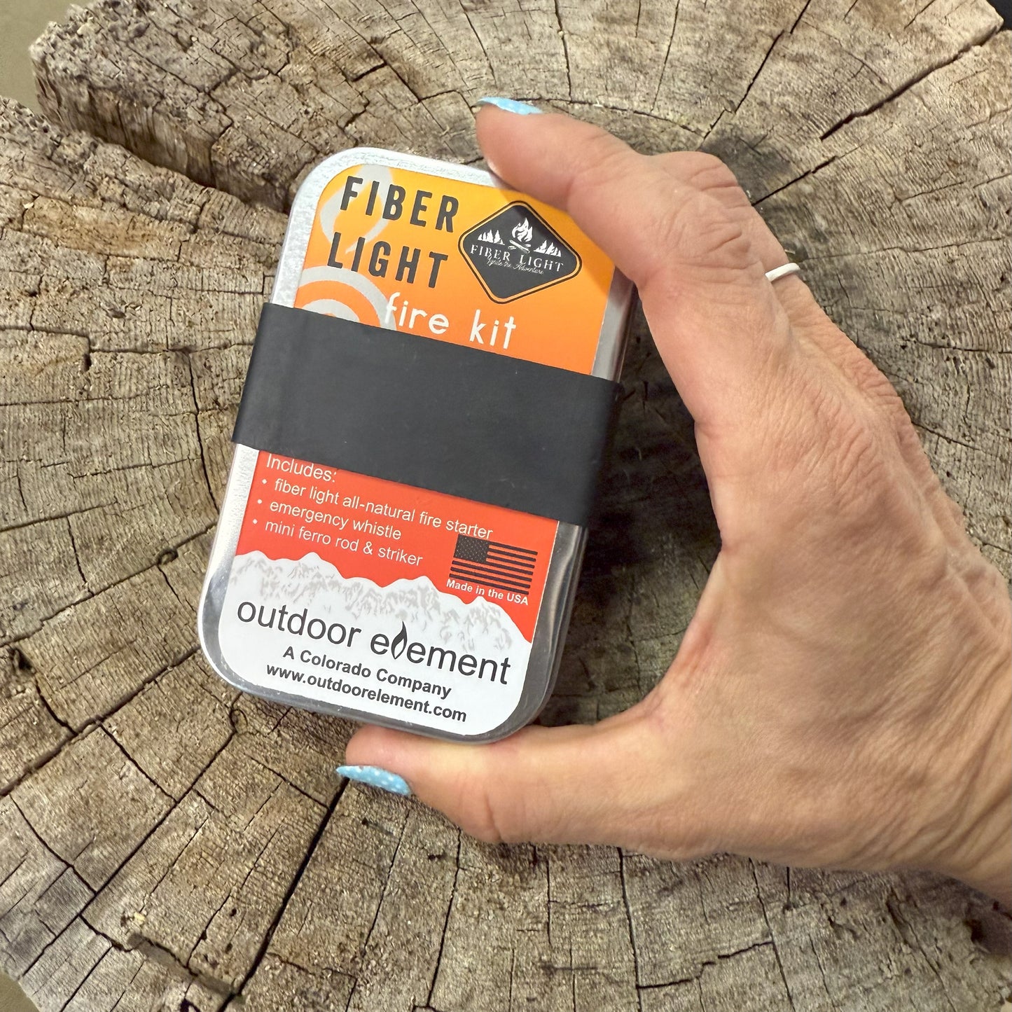 Hand holding a Fiber Light fire kit against a wooden background